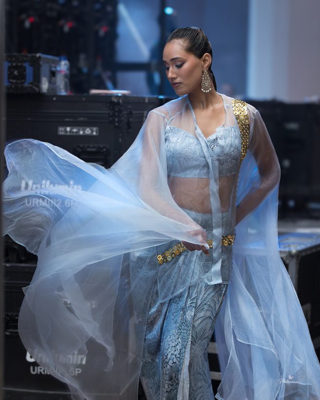 Model in a flowing pale blue gown on the runway